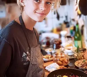 Un adolescent débrouillard s'activant en cuisine avec un large sourire, préparant un plat avec application et enthousiasme