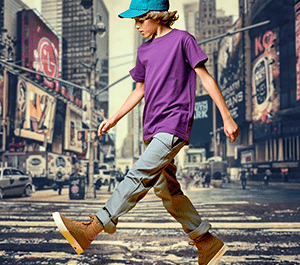 Jeune adolescent en tenue streetwear traversant une rue en ville, casquette et sneakers, ambiance urbaine moderne et dynamique.