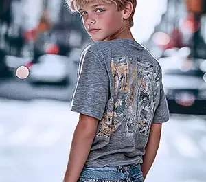 Adolescent blond en t-shirt gris imprimé et jean délavé, style streetwear urbain décontracté, arrière-plan ville floue